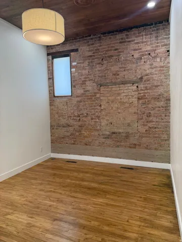 Exposed brick accent wall, wood-finish flooring, wood plank ceiling, and recessed lighting