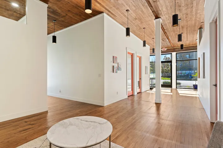 Exposed wood beam ceiling with recessed lighting, wood-finish flooring, full-height windows, and interior doors with glass panels