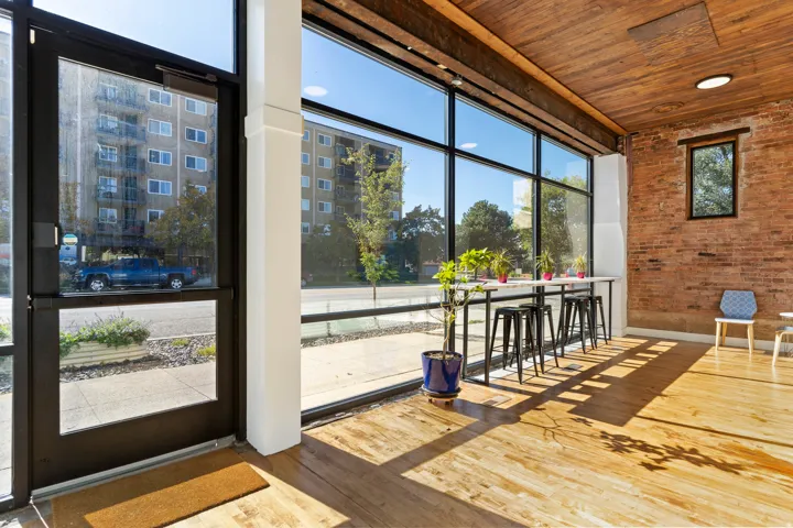 Exposed brick wall, natural wood-finish flooring, wood-plank ceiling, and expansive windows
