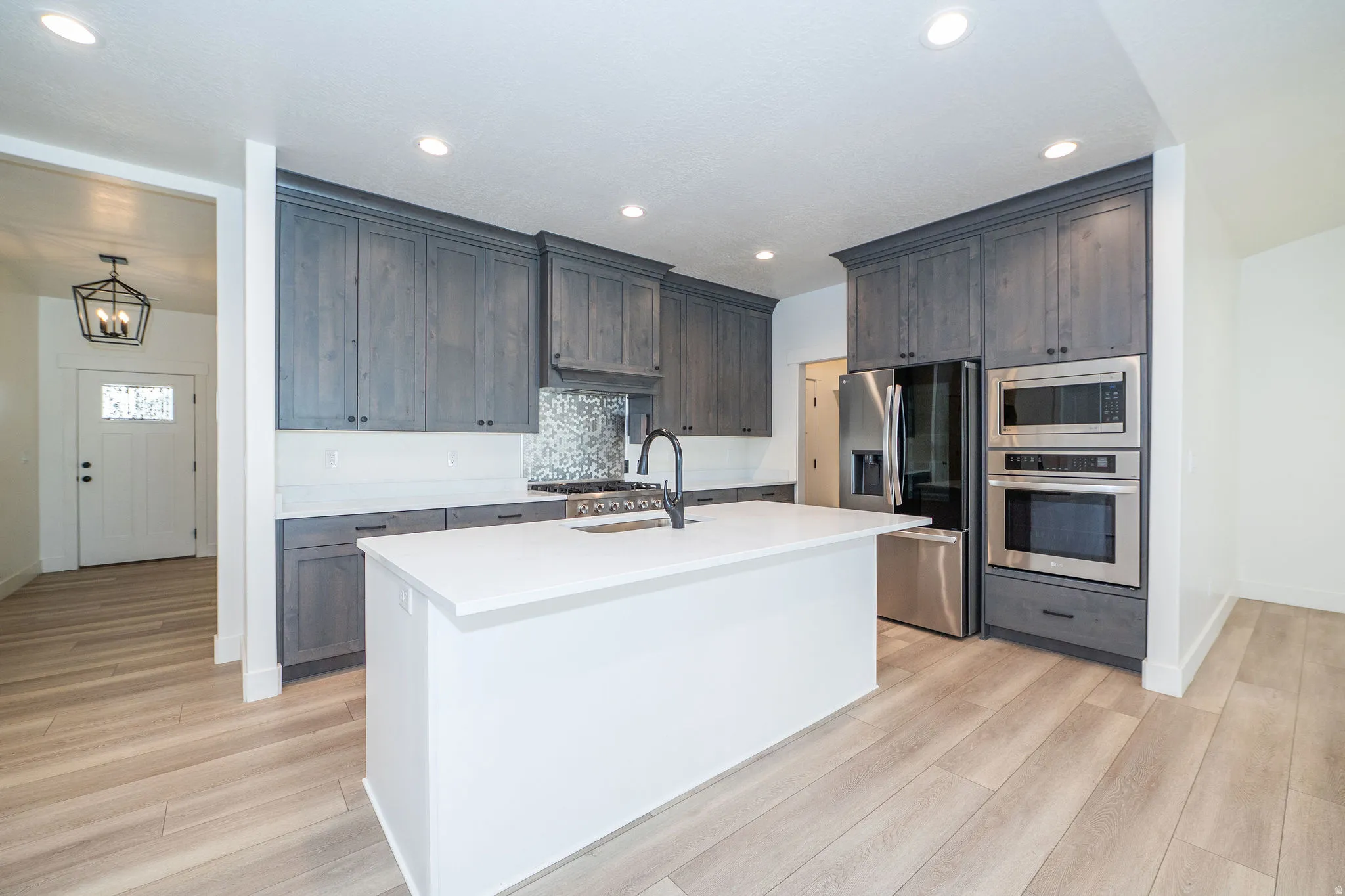 Kitchen featuring dark gray cabinetry, stainless steel appliances, a white island, white countertops, and light wood-finish flooring