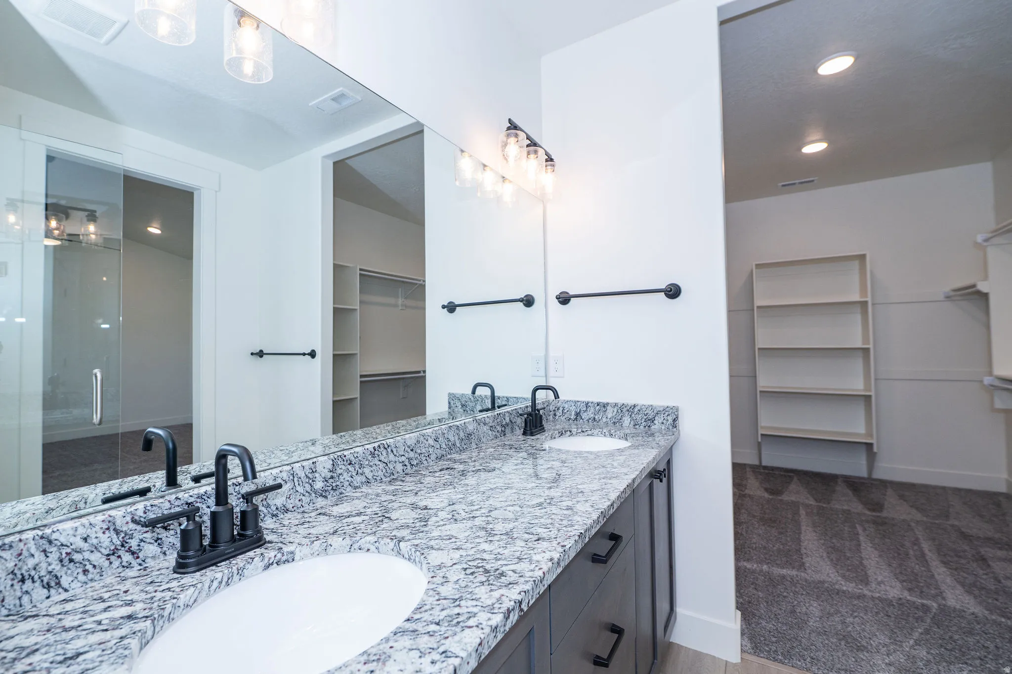 Dual undermount sinks set in a stone-finish countertop with dark cabinetry