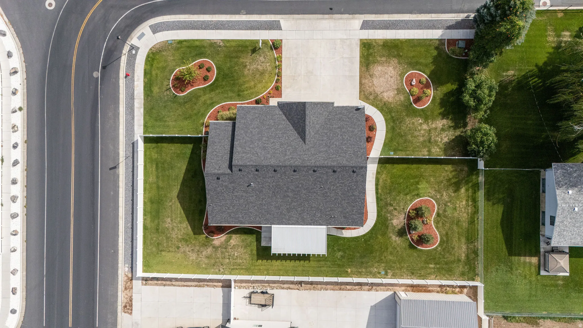 Manicured front yard with mature landscaping, a paved driveway, and established sidewalks
