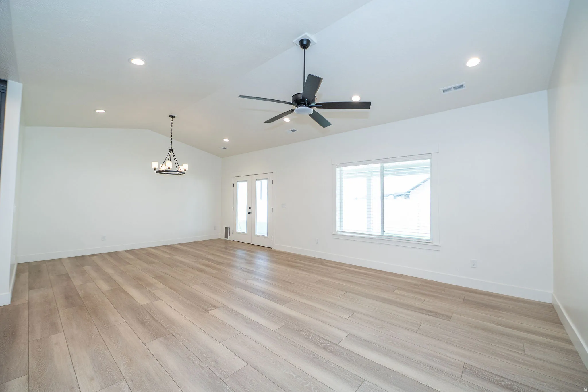 Vaulted ceiling with recessed lighting, wood-finish flooring, and a contemporary chandelier