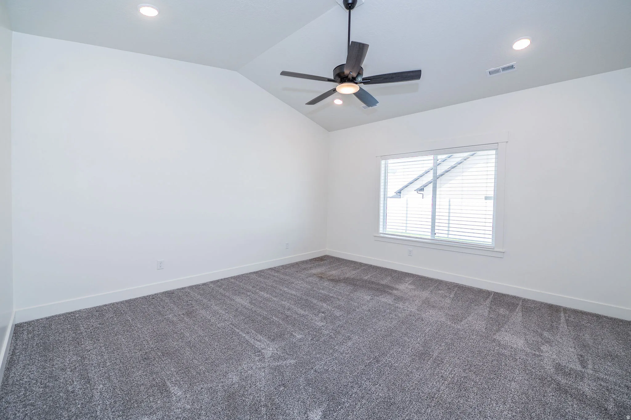 Vaulted ceiling with a contemporary ceiling fan, recessed lighting, and a large window with blinds