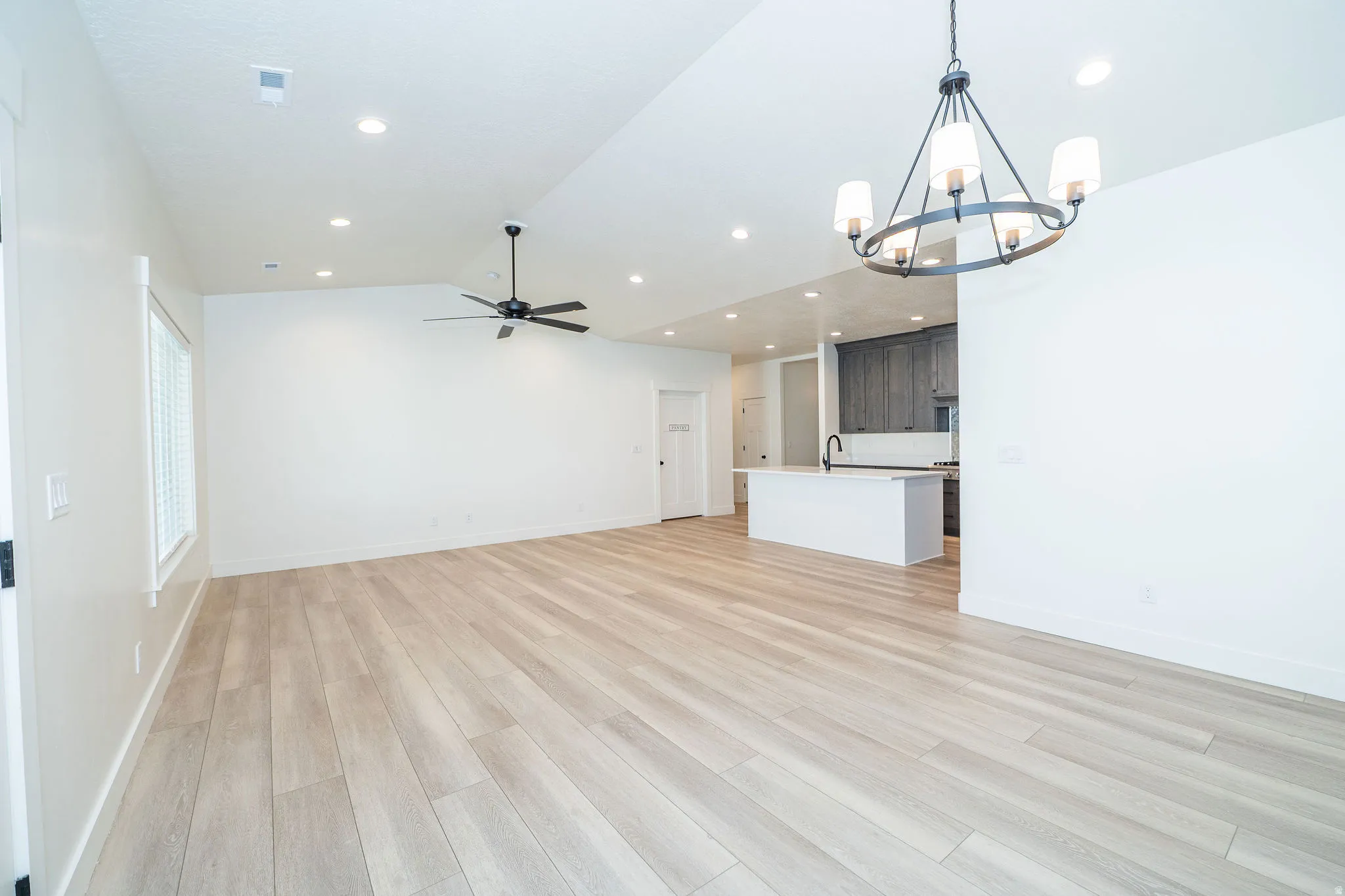 Light wood-finish flooring with recessed lighting and a ceiling fan
