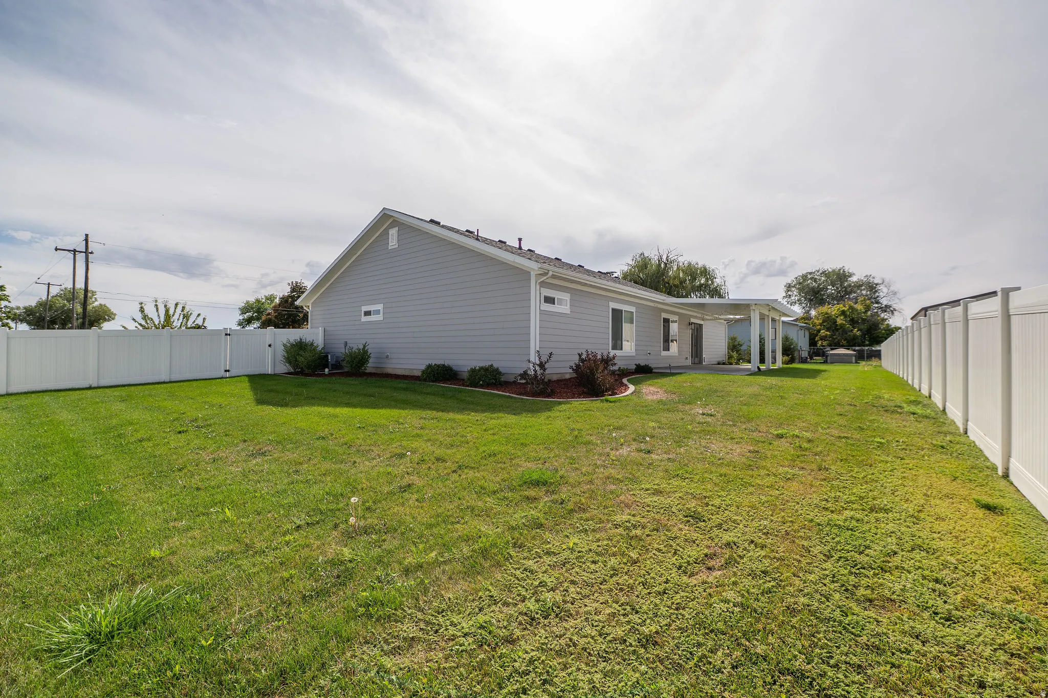 Expansive lawn area with a white privacy fence