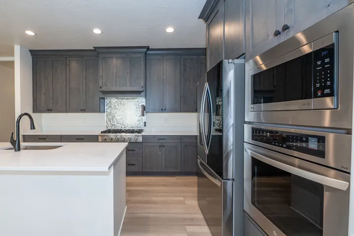 Kitchen featuring gray cabinetry, stainless steel appliances, a center island with sink, and wood-finish flooring