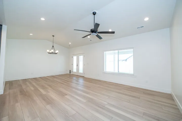 Vaulted ceiling with recessed lighting, wood-finish flooring, and a contemporary chandelier