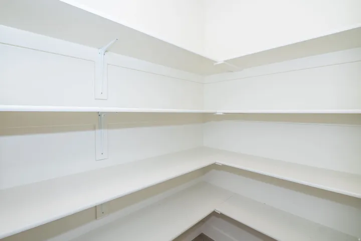 Walk-in closet with extensive built-in shelving, white finish, and a hanging rod