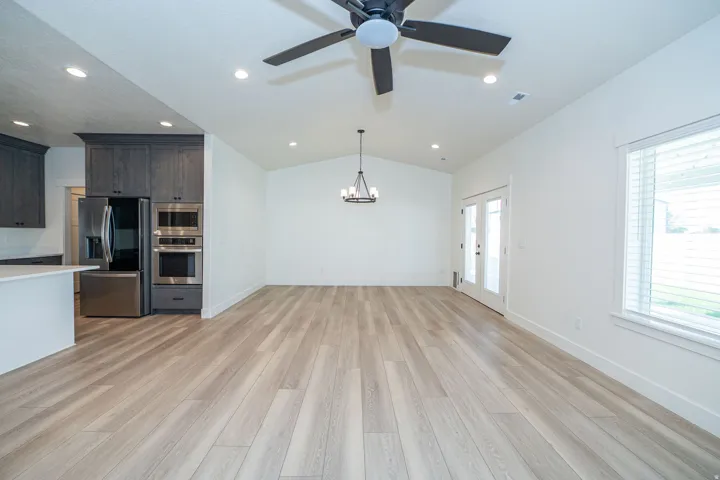 Vaulted ceiling with recessed lighting and ceiling fan, wood-finish flooring, white walls, and French doors