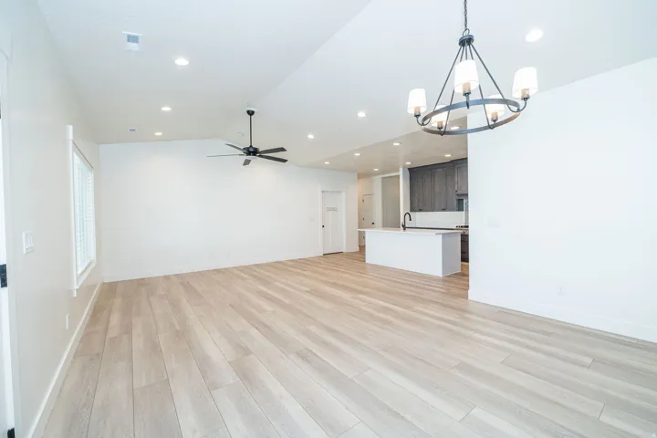 Light wood-finish flooring with recessed lighting and a ceiling fan
