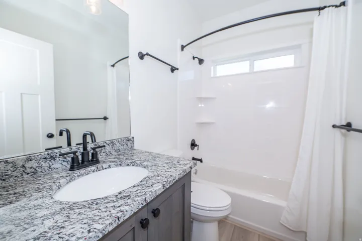 Bathroom featuring a vanity with a white countertop and an integrated sink, a dark wood-finish cabinet, and a matte black faucet