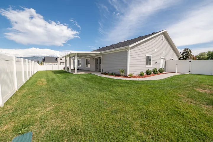 Expansive backyard with a full perimeter fence, covered patio, and a separate side entrance