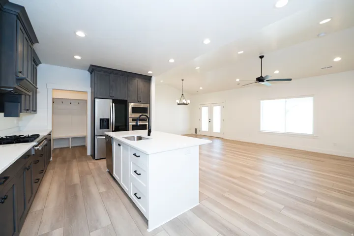 Kitchen with dark wood-finish cabinetry, stainless steel appliances, a center island with sink, and light wood-finish flooring