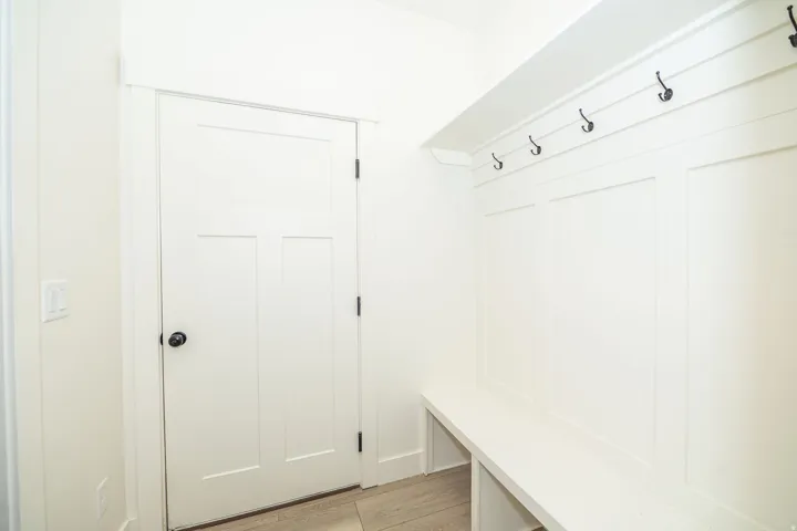Built-in hall tree with storage bench, wall paneling, and black coat hooks