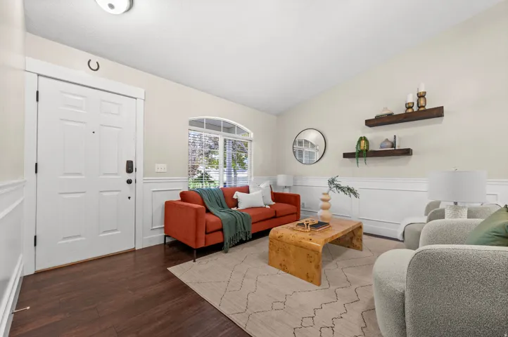 Arched window with blinds, wood-finish flooring, white paneled wainscoting, and accent wall shelving