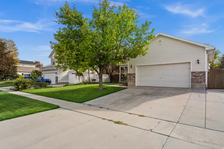 Spacious concrete driveway, attached two-car garage, and a lush green lawn