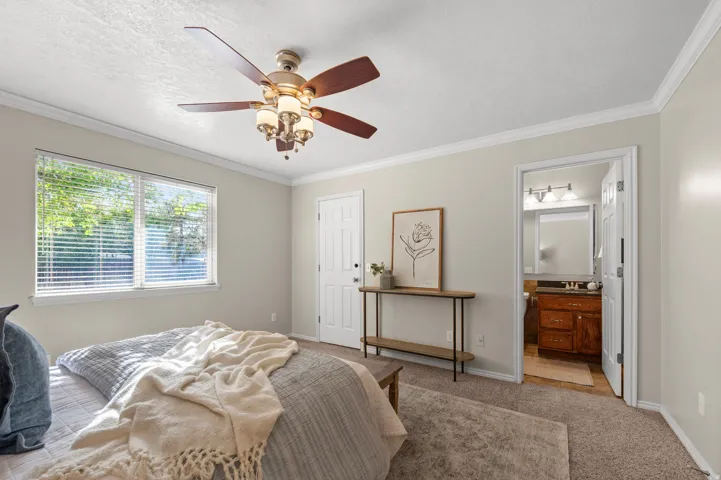 Ceiling fan with integrated lighting, a bright window with blinds, and white trim molding throughout