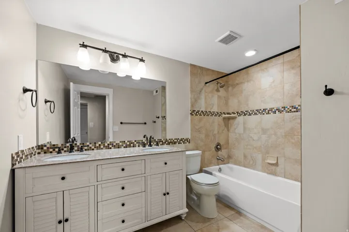 Dual vanity with shaker-style cabinetry, double undermount sinks, and a mosaic tile backsplash