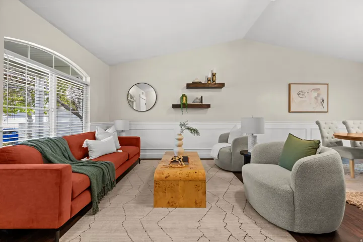 Vaulted ceiling, arched window, wainscoting, wood-finish flooring, and wall-mounted shelving