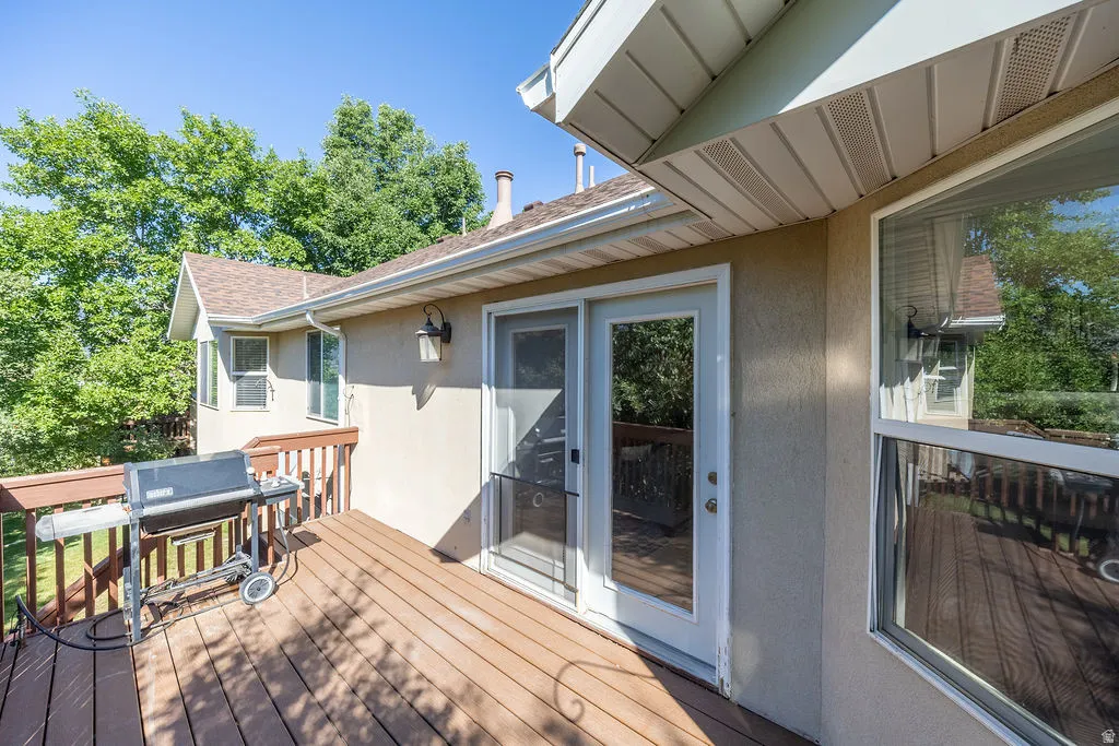 Wood-finish deck with a wood railing, exterior lighting, and stucco siding