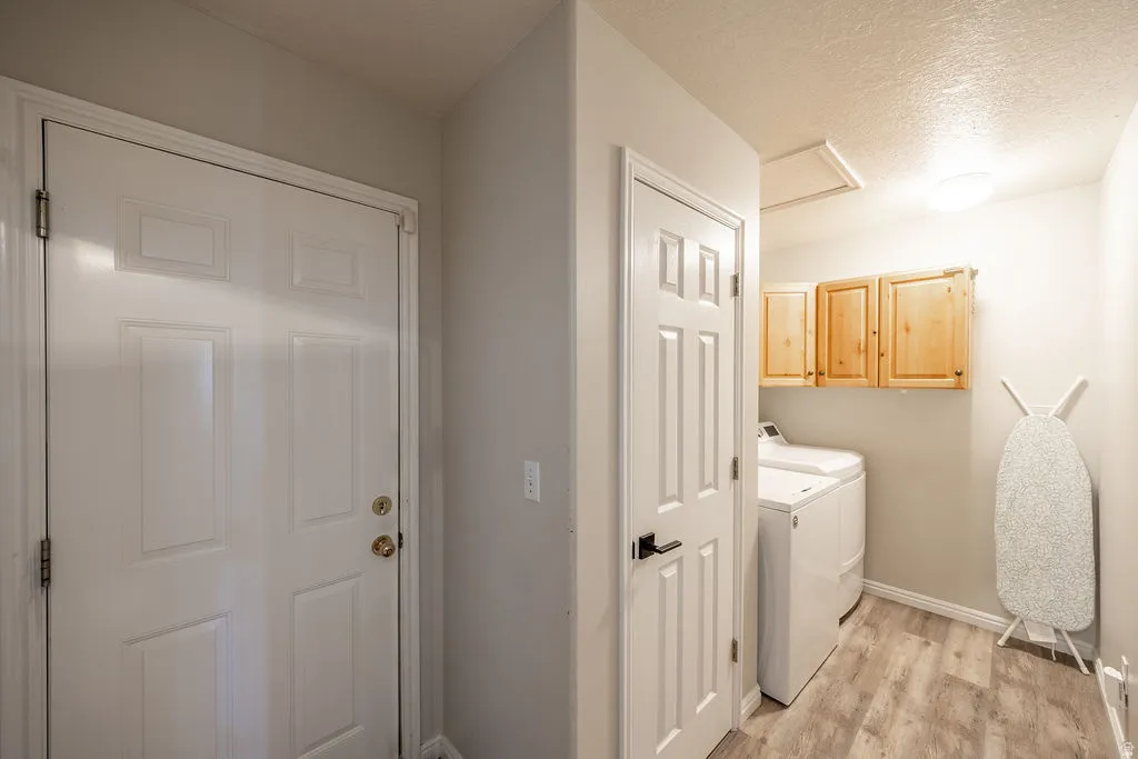 Dedicated laundry area featuring overhead cabinetry and wood-finish flooring