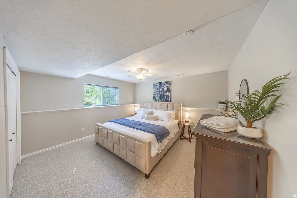 Primary Bedroom Suite with Vaulted Ceiling and Natural LightSpacious primary bedroom features a vaulted ceiling with recessed lighting, abundant natural light from dual windows, and neutral wall finishes with wainscoting detail