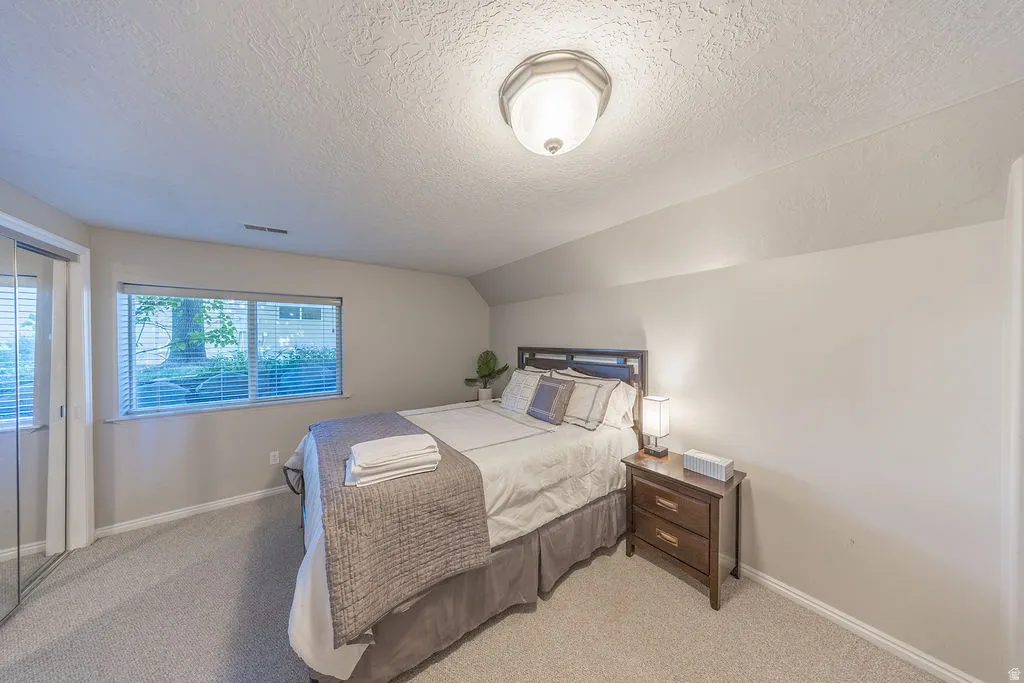Wall-to-wall carpeting with a large window and mirrored closet doors