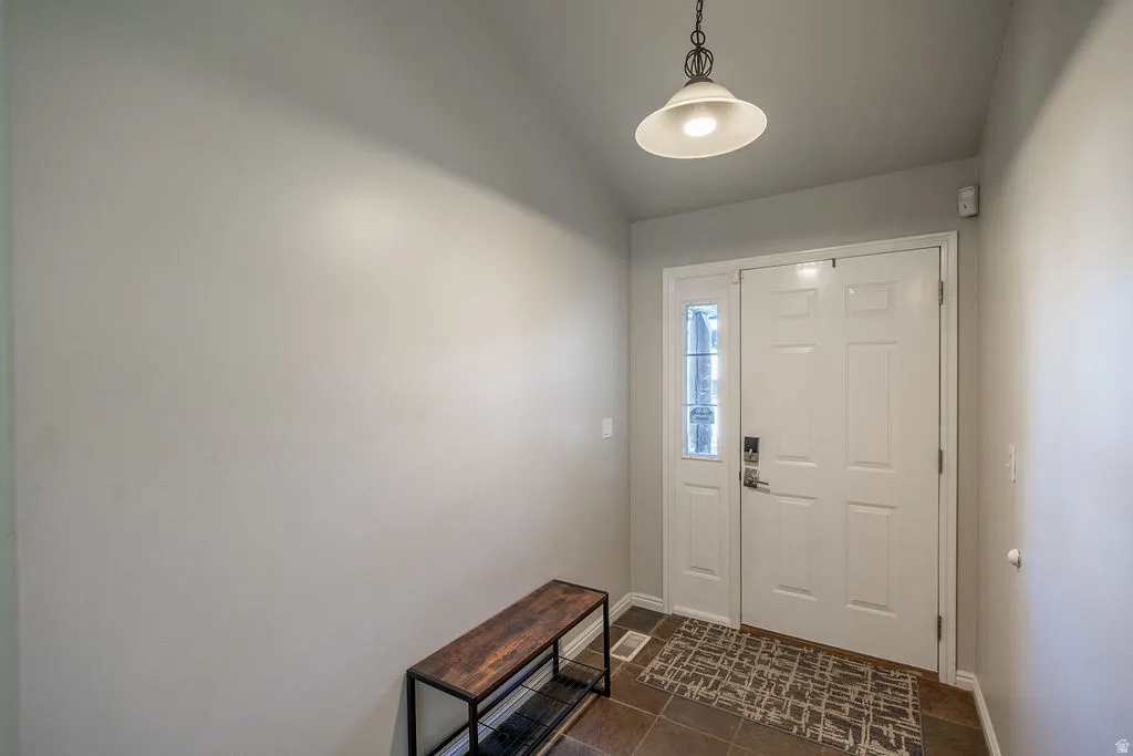 White paneled entry door with a sidelight, recessed ceiling, and a hanging pendant light fixture