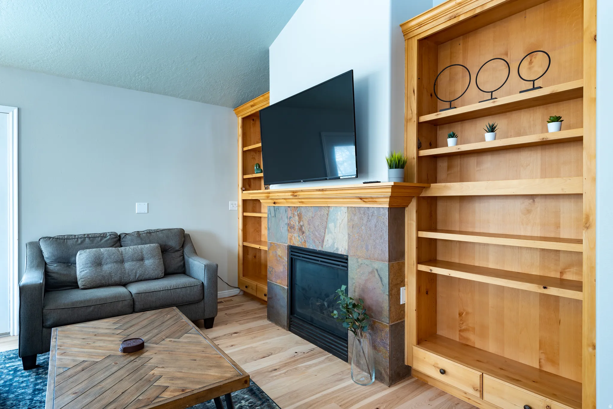 Built-in shelving units, wood-finish flooring, stone-clad fireplace, vaulted ceiling