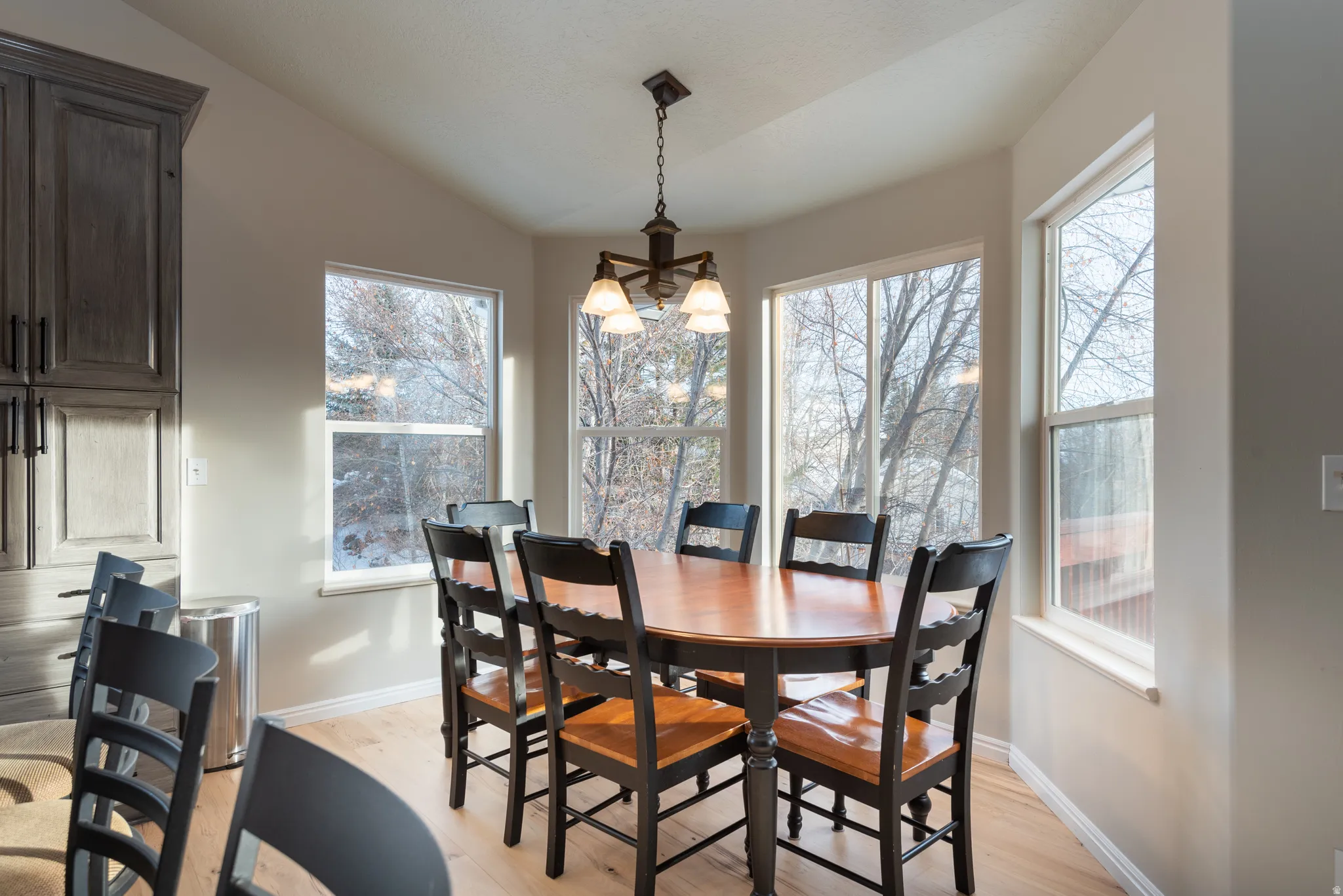 Angled wall featuring multiple windows, sloped ceiling, wood-finish flooring, and dark-toned built-in cabinetry