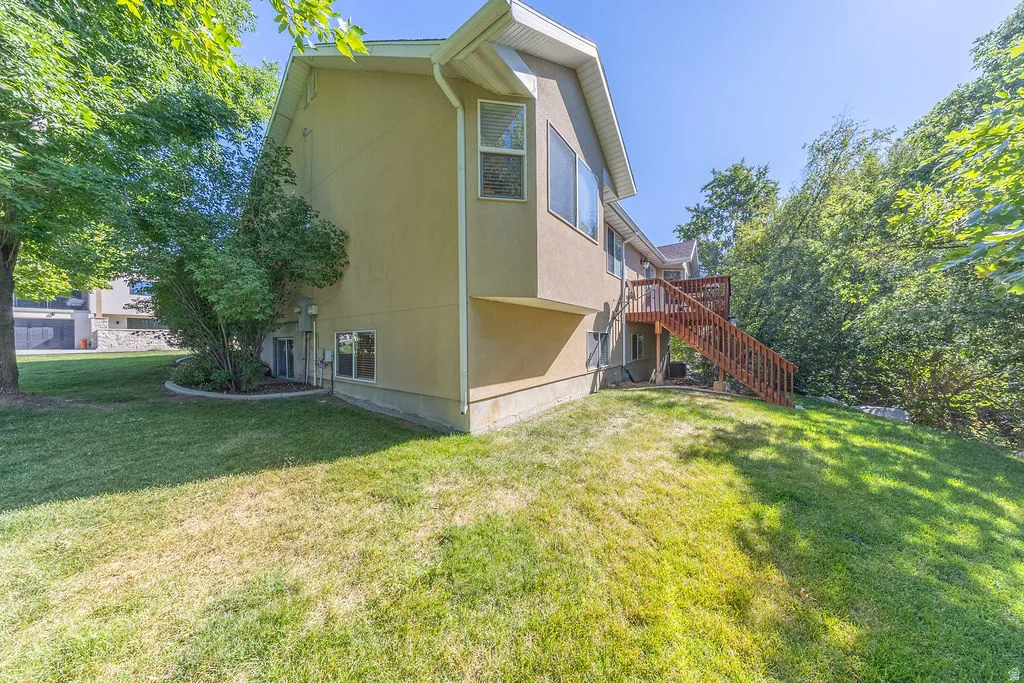 Exterior featuring stucco siding, multiple windows, a wood deck, and mature landscaping
