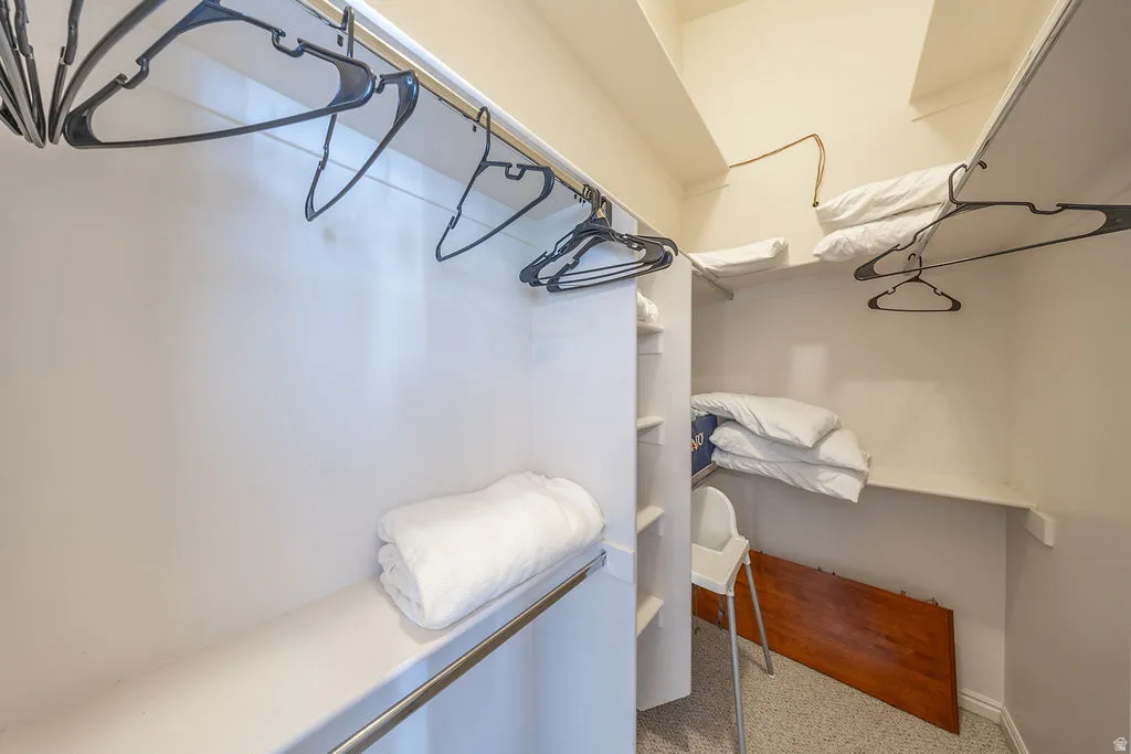 Walk-in closet featuring multiple hanging rods, built-in shelving, and a neutral color palette