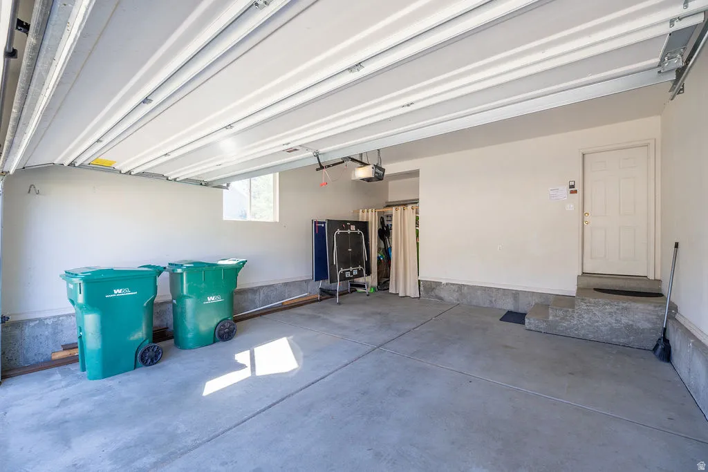 Attached overhead garage door, concrete flooring, interior access door, window, built-in storage area