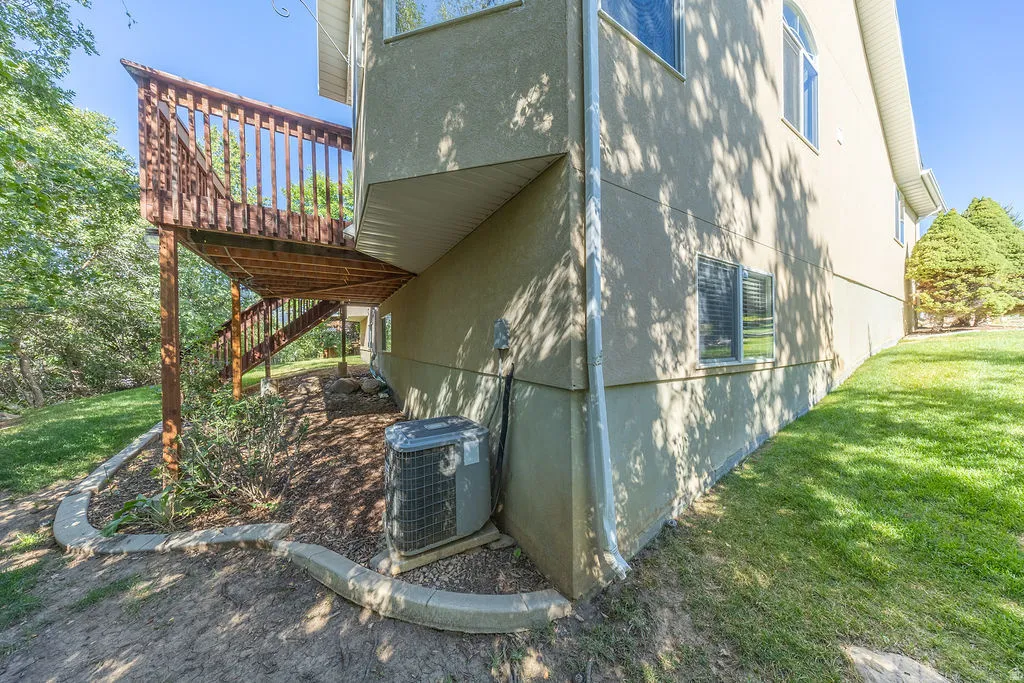 Exterior deck with wood railings, stucco siding, and a sloped, landscaped yard