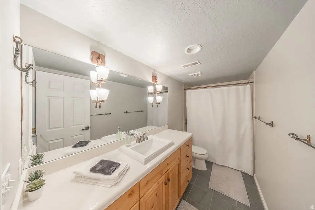 Double vanity with light wood-finish cabinetry, integrated sinks, and expansive mirror