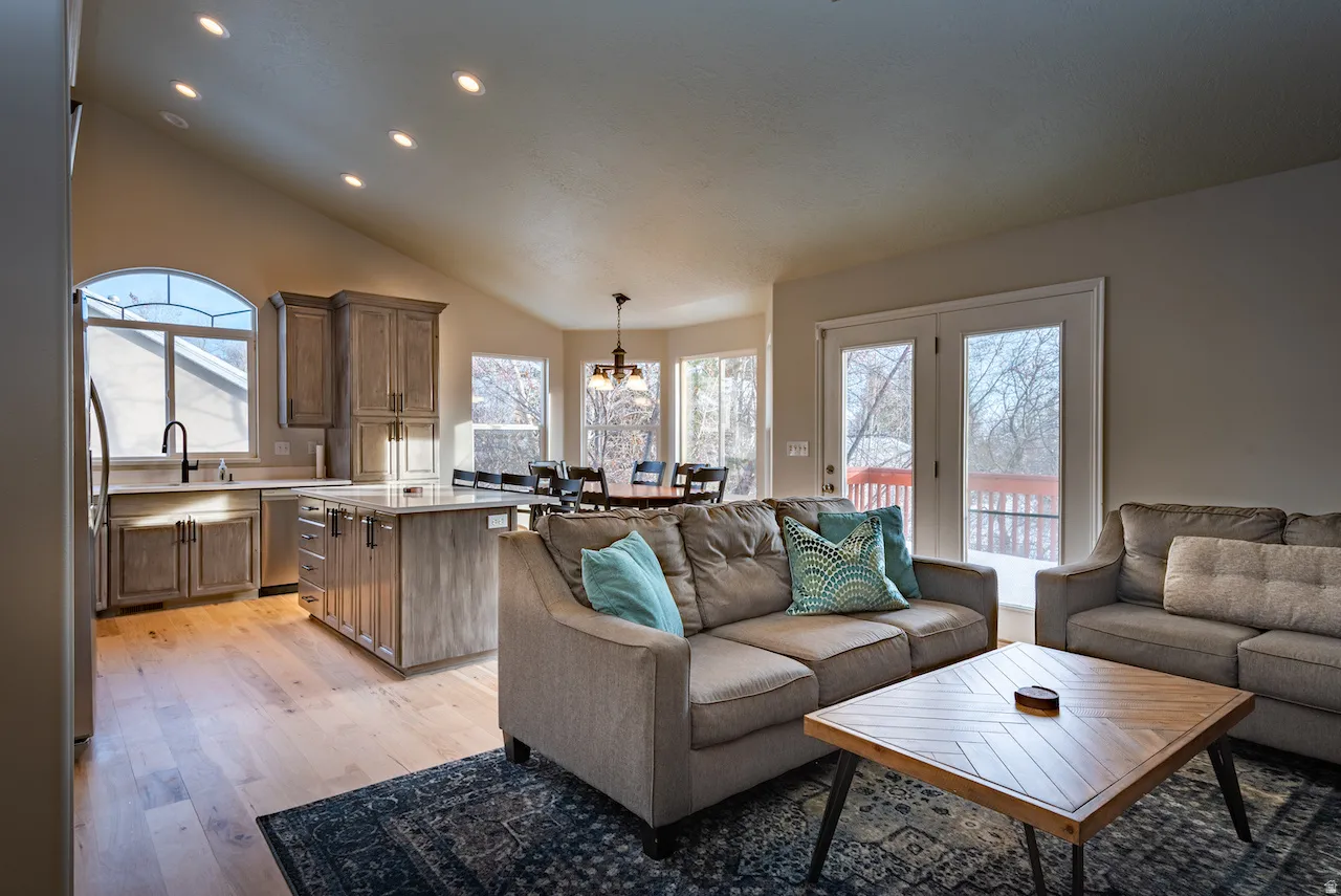Vaulted ceiling with recessed lighting, wood-finish flooring, kitchen island with built-in storage, French doors, and an arched window