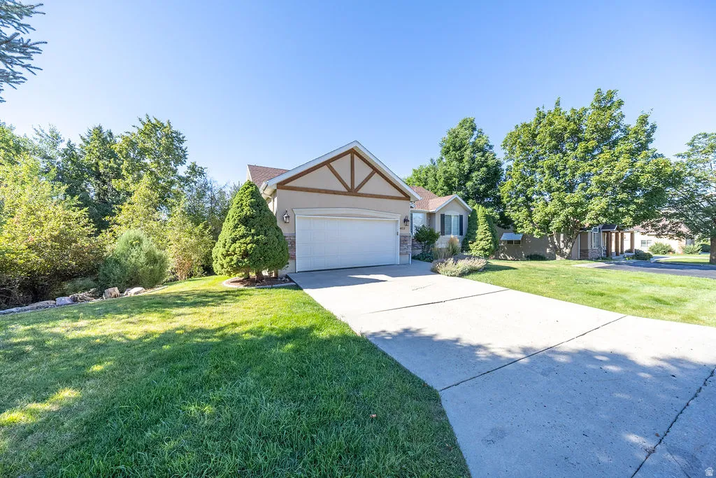 Exterior featuring a two-car garage, concrete driveway, and mature landscaping