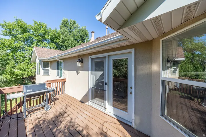 Wood-finish deck with a wood railing, exterior lighting, and stucco siding