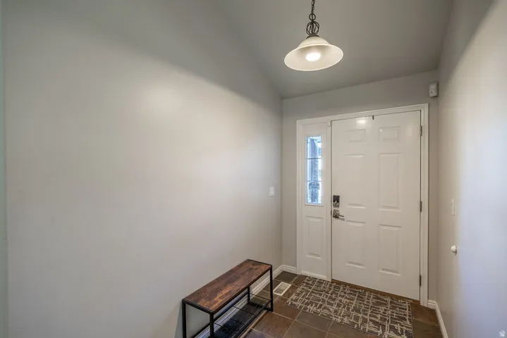 White paneled entry door with a sidelight, recessed ceiling, and a hanging pendant light fixture