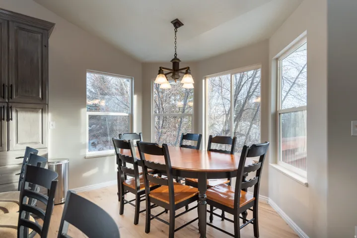 Angled wall featuring multiple windows, sloped ceiling, wood-finish flooring, and dark-toned built-in cabinetry