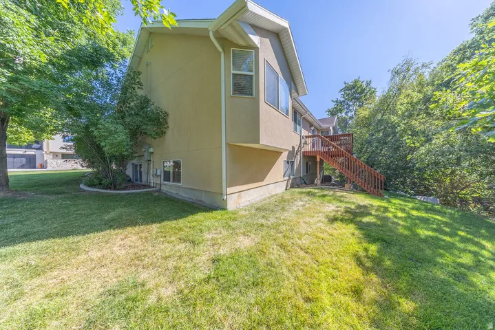 Exterior featuring stucco siding, multiple windows, a wood deck, and mature landscaping