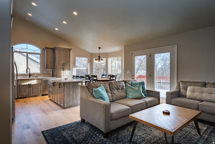 Vaulted ceiling with recessed lighting, wood-finish flooring, kitchen island with built-in storage, French doors, and an arched window