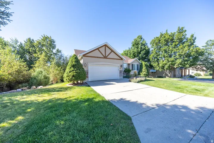 Exterior featuring a two-car garage, concrete driveway, and mature landscaping