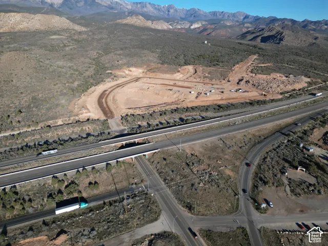 Expansive undeveloped land featuring graded areas, direct highway access, mountain scenery, and established roadways