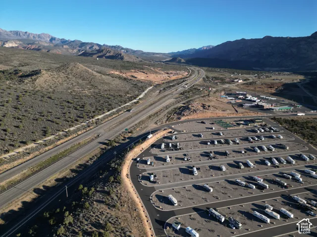 Extensive paved lot with multiple marked spaces, adjacent to an interstate highway, with distant mountains