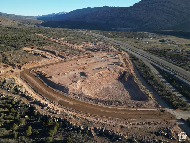 Expansive cleared development site featuring excavated areas, graded access roads, and highway proximity
