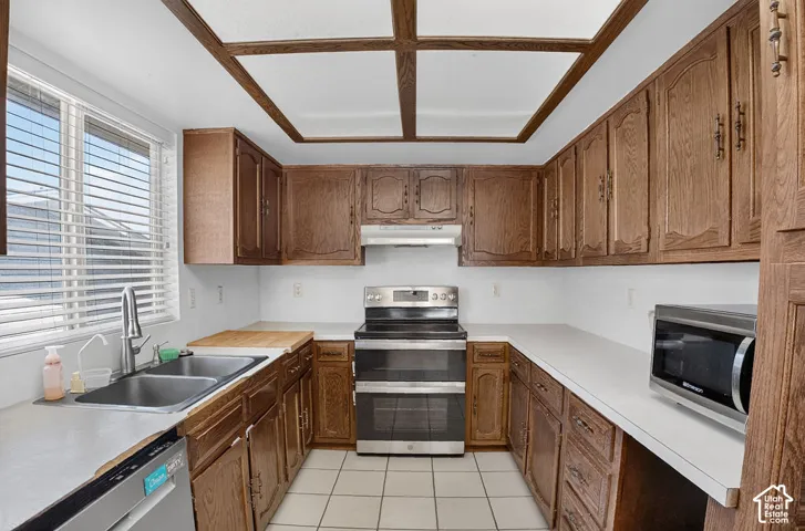 Kitchen featuring wood cabinetry, white countertops, a stainless steel range, and tile flooring