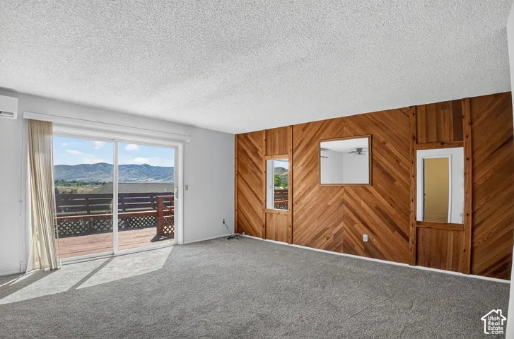 Sliding glass doors opening to an outdoor deck, a wood-paneled accent wall with a chevron pattern, and a mini-split air conditioning unit