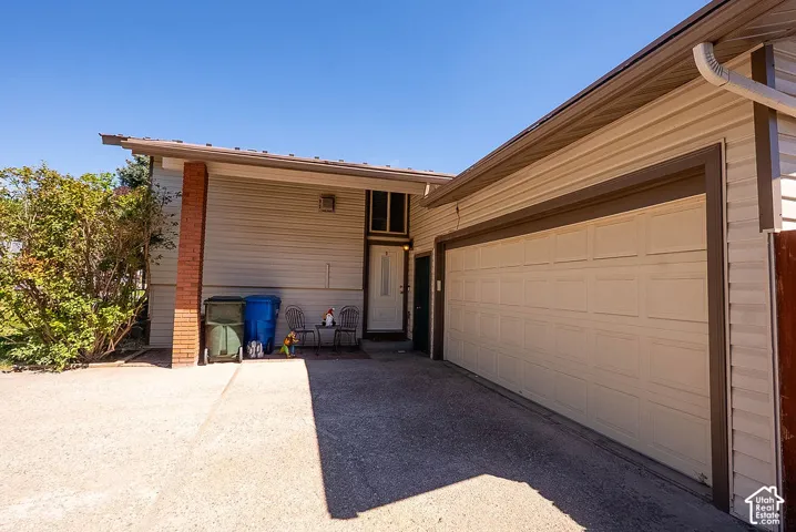 Attached two-car garage with paneling, brick column accent, and light-colored siding